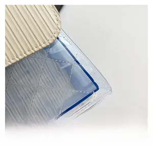 Detail of epi-patterned faux leather flap and quilted transparent PVC crossbody bag
