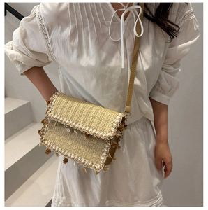 Detail of straw woven crossbody bag with fringe tassels and sea shell decor on white dress