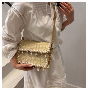 Dettaglio borsa a tracolla in paglia intrecciata a mano con nappe di conchiglie e perline