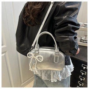 Detail of silver metallic pillow bag with pearl bow charm and heart pendant