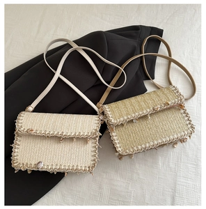 Detail of woven straw crossbody bags showing intricate shell trim and herringbone texture