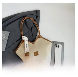 Detail of beige canvas tote with brown leather trim and decorative scarf for work