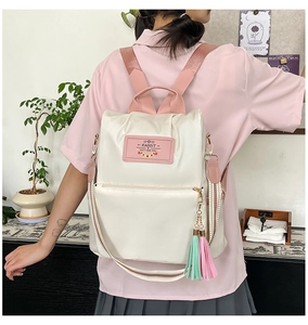 Detail of casual nylon backpack with pink heart label and colorful tassel accessories