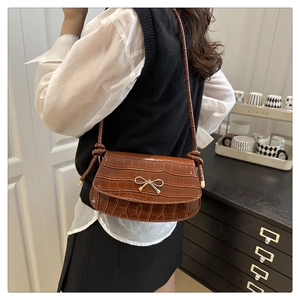 Brown crocodile pattern shoulder bag featuring a gold bow accent and knotted strap detail