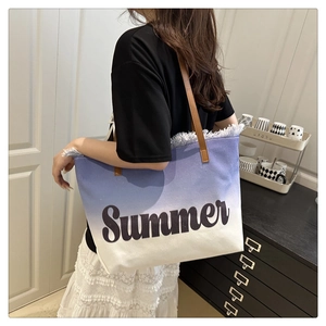Détail d'un cabas de plage en toile dégradé bleu avec lettrage Summer et anses cuir