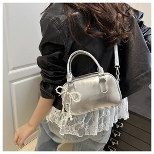 Silver metallic bowling bag styled on model with a cute pearl bow charm detail
