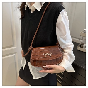 Detail of vintage brown faux crocodile leather bag featuring a gold bow buckle clasp