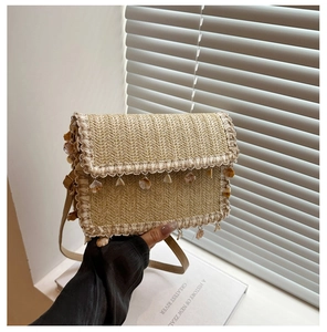 Close-up of woven straw bag with boho shell charms and wave tassels for seaside vacation