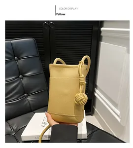 Detail der gelben Crossbody-Tasche aus Narbenleder mit runder Knotenschulterriemen