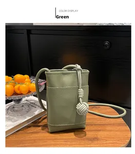 Grüne Mini-Umhängetasche aus Leder mit Knotendetail auf einem Holztisch präsentiert