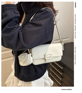 Detail of white litchi texture baguette bag with small chain pouch on shoulder