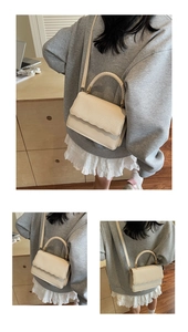 Detail of cream crossbody bag with woven texture handle and wavy edge flap design