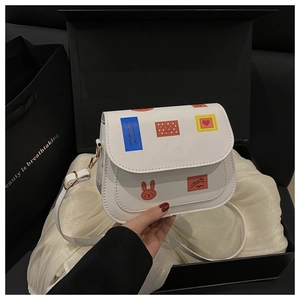 Détails d'un petit sac bandoulière blanc avec imprimés cartoon et fermeture magnétique