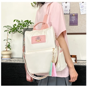 Detail view of cream Oxford cloth backpack with pink straps and a decorative rabbit patch