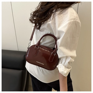 Close-up of a burgundy patent leather bowling bag showing glossy finish and silver hardware