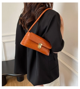 Brown crocodile embossed shoulder bag with gold clasp shown on model in black blazer