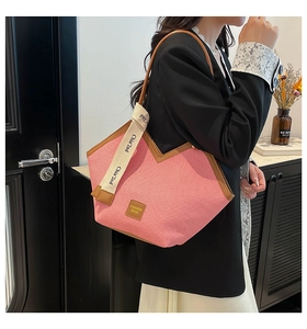 Detail view of pink canvas tote with brown leather trim and wide textile strap on shoulder