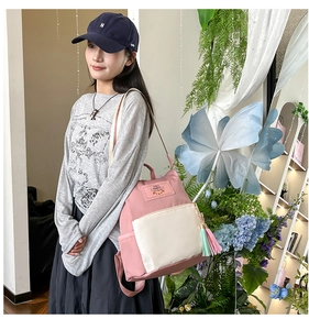 Detail of pink and beige nylon backpack showing contrast zippers and cute rabbit logo tag