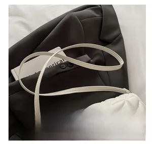 Close-up of white quilted crossbody bag with gold metal lock and leather texture