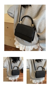 Detail of black crossbody bag with woven handle, gold hardware and texture contrast