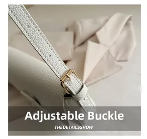 Detail of adjustable golden metal buckle on white pebble leather shoulder bag strap
