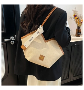 Detail of canvas tote bag with brown leather trim and fashion ribbon on the shoulder