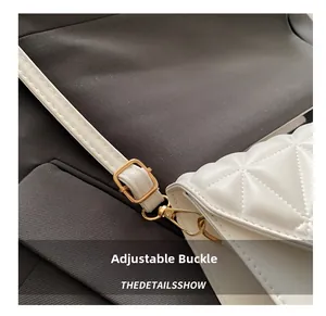Detail of adjustable golden buckle and triangle quilted leather on a white crossbody bag