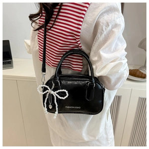Close-up of black glossy bowling bag with pearl bow charm and Fashion & Bag text
