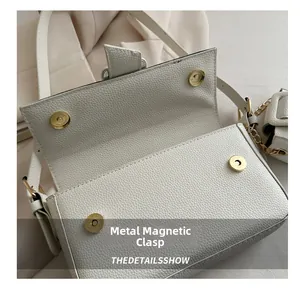 Detail of white lychee leather baguette bag showing four golden magnetic snap closures