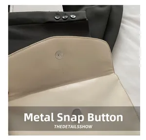 Detail view of the magnetic hardware buckle on a beige minimalist leather handbag