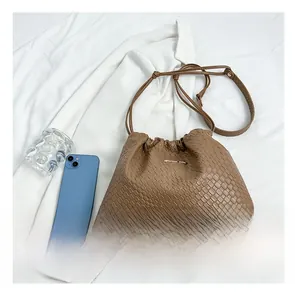 Confronto dimensioni di una borsa a secchiello intrecciata marrone con smartphone