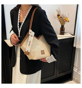 Close-up of beige woven tote bag with V-shaped leather trim and Chia'2nd ribbon detail