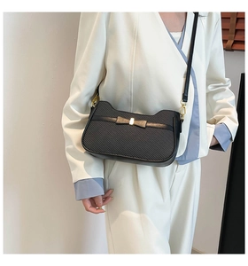 Close-up of black herringbone fabric shoulder bag with metallic bow detail and strap