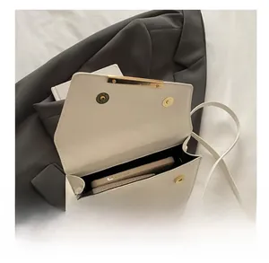 Top-down view showing the spacious interior of a quilted cream crossbody bag with a smartphone