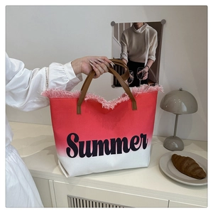 Détail du cabas en toile dégradé rouge avec lettrage Summer et bordures à franges de plage