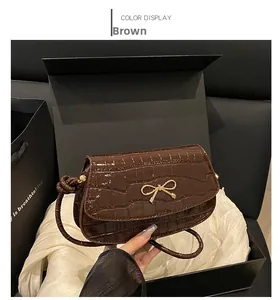 Dettaglio della borsa in pelle marrone coccodrillo con fibbia metallica a fiocco