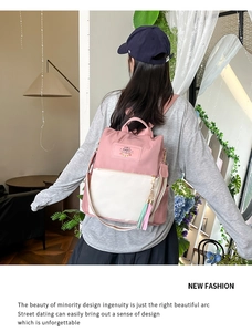 Detailed view of pink and white nylon backpack with Rabbit patch and tassel charm