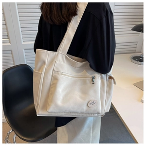 Detailed view of cream canvas tote bag with functional pockets and Good Luck patch