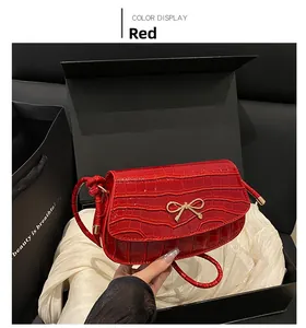 Dettaglio borsa rossa con trama coccodrillo e fibbia dorata in scatola regalo