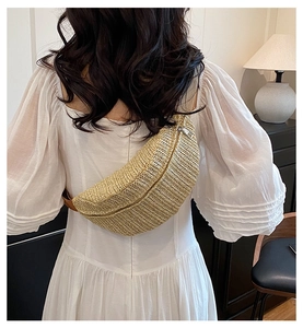 Detailed view of woven straw crescent bag with zipper and adjustable crossbody strap