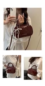 Detail of burgundy bowling bag featuring glossy finish and pearl bow charm accessory