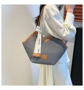 Detail view of a large vintage canvas tote bag with brown leather trim and fashion tag