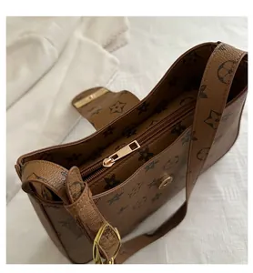 Detail view of smooth golden zipper and magnetic buckle on vintage brown patterned handbag