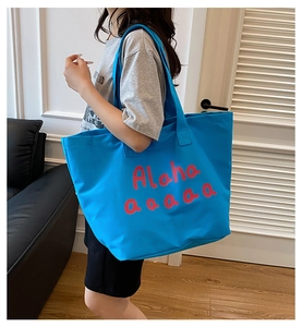 Detail of blue canvas tote bag with pink letter print and wide shoulder strap