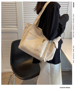 Detailed side view of an off-white large capacity tote bag with front zipper pocket