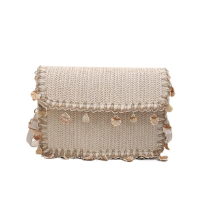 Straw crossbody bag with shell charms and leather strap for summer beach vacations