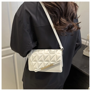 Back view of a model wearing a white quilted crossbody bag with golden metal trim