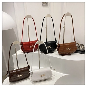 Detailed display of five crocodile pattern crossbody bags with golden bow buckles