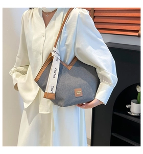 Detail of blue denim tote bag with brown leather trim and fashion decorative strap