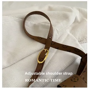 Detail of adjustable brown leather shoulder strap with golden oval buckle and monogram pattern
